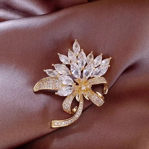 Elegant gold flower brooch with marquise stones and crystal ribbon on silk background