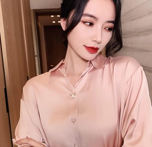 Detailed close-up of a pink satin shirt collar featuring a luxury pearl bee brooch pin