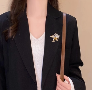 Detail of a sparkling flower brooch with crystals on a black suit lapel for women