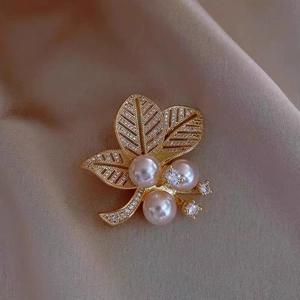 Eleganter Blatt-Brosche mit drei rosa Perlen und funkelnden Zirkonen auf Satinstoff
