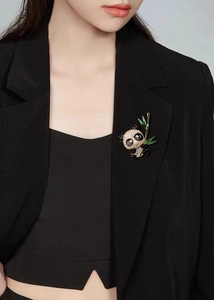Détail d'une broche panda en cristal et bambou doré sur le revers d'un tailleur