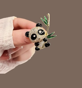 Détail d'une broche panda avec cristaux scintillants et bambou vert vue en main