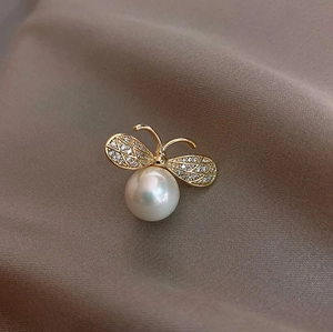 Macro shot of gold bee brooch with a large pearl abdomen and sparkling crystal wings