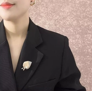 Close-up of maple leaf brooch with pearl on a black suit jacket for elegant styling