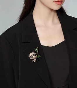 Détail d'une broche panda avec cristaux scintillants et bambou vert sur une veste noire