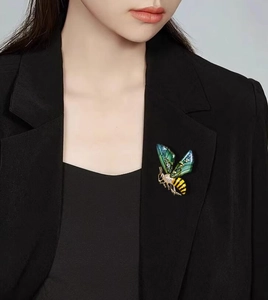 Detailed macro shot of a green bee brooch with crystals on a black suit lapel