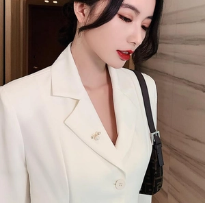 Elegant bee pearl brooch with crystals pinned on a white blazer lapel for styling