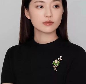 Exquisite golden lotus brooch with green leaves and white pearls on a black jacket