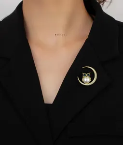 Detailaufnahme einer Mond-Eule-Brosche mit weißer Perle auf einem schwarzen Blazer