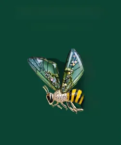 Detail of honey bee brooch with green wings and crystal pave setting on dark background
