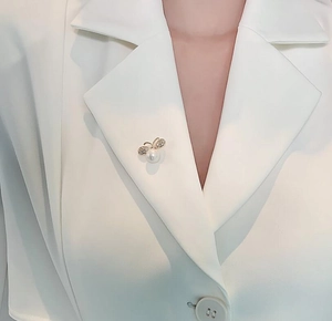 Close-up of butterfly pearl brooch with rhinestones worn on a white blazer lapel