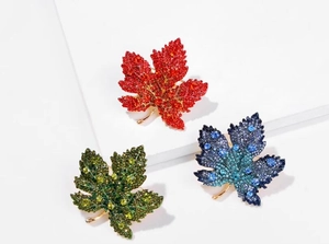Close-up of maple leaf brooches featuring vibrant red and green gradient rhinestones
