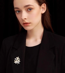 Elegant gold leaf brooch with white pearls pinned on a formal black blazer jacket