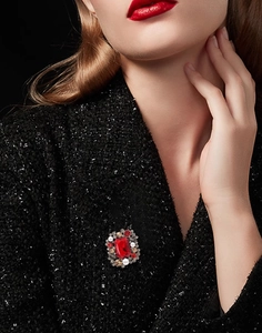 Detail of vintage square brooch with red faceted stone and pearls on black wool coat
