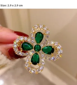 Vue macro d'une broche trèfle vintage de 2,9cm avec des pierres vert émeraude