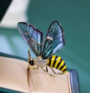 Detail of bee brooch with gradient wings and pavé crystals on a green jewelry box