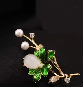 Detailed close-up of a lotus flower brooch with pearls, green enamel leaves, and gemstones