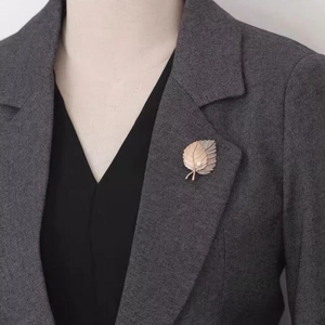 Detail of two-tone maple leaf brooch with pearl on a grey suit lapel