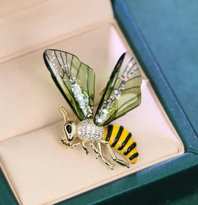 Macro view of exquisite bee brooch with green wings and yellow enamel details