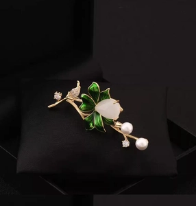 Detailed macro view of bird and lotus brooch with green enamel on black jewelry box