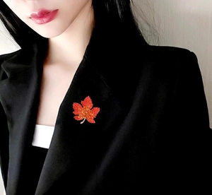 Close-up of a luxury red maple leaf brooch with crystals on a black suit lapel