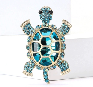 Macro detail of turtle brooch with blue crystals and glittering rhinestones on gold base
