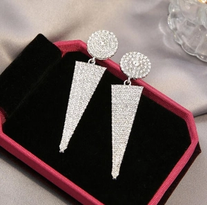 Detail of silver round geometric earrings with white rhinestones on luxury velvet box