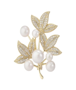 Macro detail of luxury leaf brooch with gold plating, white pearls and sparkling zircons