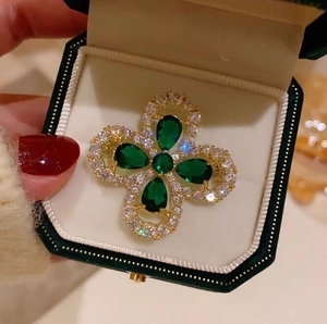 Broche trèfle doré avec pierres vert émeraude et entourage de cristaux blancs fins