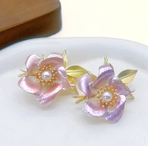Macro shot of camellia flower pin with pink gradient petals and a pearl center
