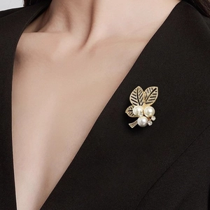 Eleganter goldener Blättern-Brosche mit weißen Perlen und kleinen Diamanten auf Anzug