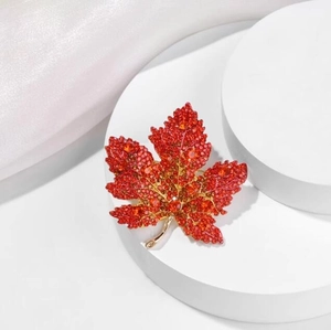 Luxurious red maple leaf brooch with sparkling crystals and gold metallic stem on silk
