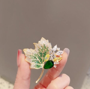 Elegant vintage gold maple leaf brooch with sparkling crystals and a green gemstone inlay