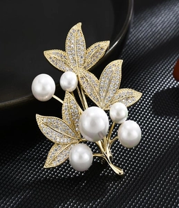 Detail of luxury leaf brooch with sparkling pavé zircons and white glossy pearls