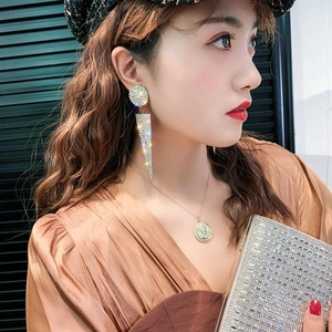 Close-up of long triangular tassel rhinestone earrings and gold coin necklace for women