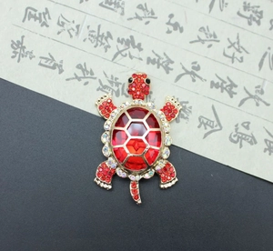 Detailed macro of golden turtle brooch featuring faceted red crystals and aurora rhinestones