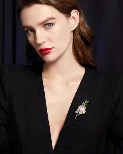 Détail d'une broche fleur avec perle blanche sur une veste en tweed noir