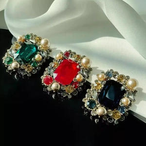 Detailed macro view of vintage square pearl brooches with emerald and ruby gemstones