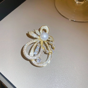 Eleganter goldener Schleifenbrosche mit Kristallen und weißer Perle auf Lederhintergrund