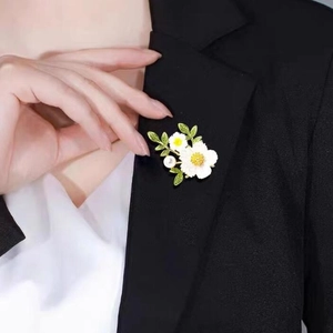 Gänseblümchen-Brosche mit weißen Blüten und Perle an einem schwarzen Revers