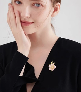 Detailed view of an elegant camellia brooch with soft pink petals and a central pearl
