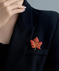 Detailed view of red maple leaf brooch with crystals on black blazer lapel