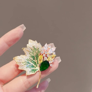 Elegant vintage hollow maple leaf brooch with green crystals and gold-tone finish