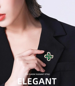 Gros plan d'une broche trèfle émeraude vintage sur un revers de veste noir chic