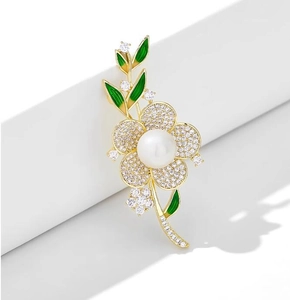 Détail de la broche fleur avec zircons blancs, perle centrale et feuilles émaillées