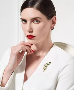 Détail de la broche élégante en perles et émail vert sur le revers d'un manteau
