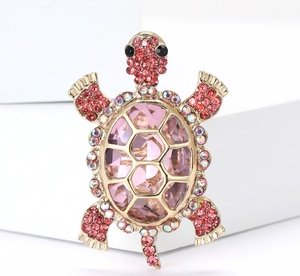 Detailed macro view of turtle brooch with pink crystals and golden alloy framework
