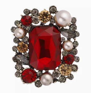 Macro detail of vintage square brooch featuring a red gemstone and white pearls