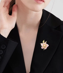 Detail of pink camellia flower brooch with pearl on a black suit jacket lapel