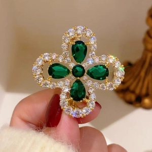 Vue détaillée de la broche trèfle avec pierres vert émeraude et pavé de cristaux